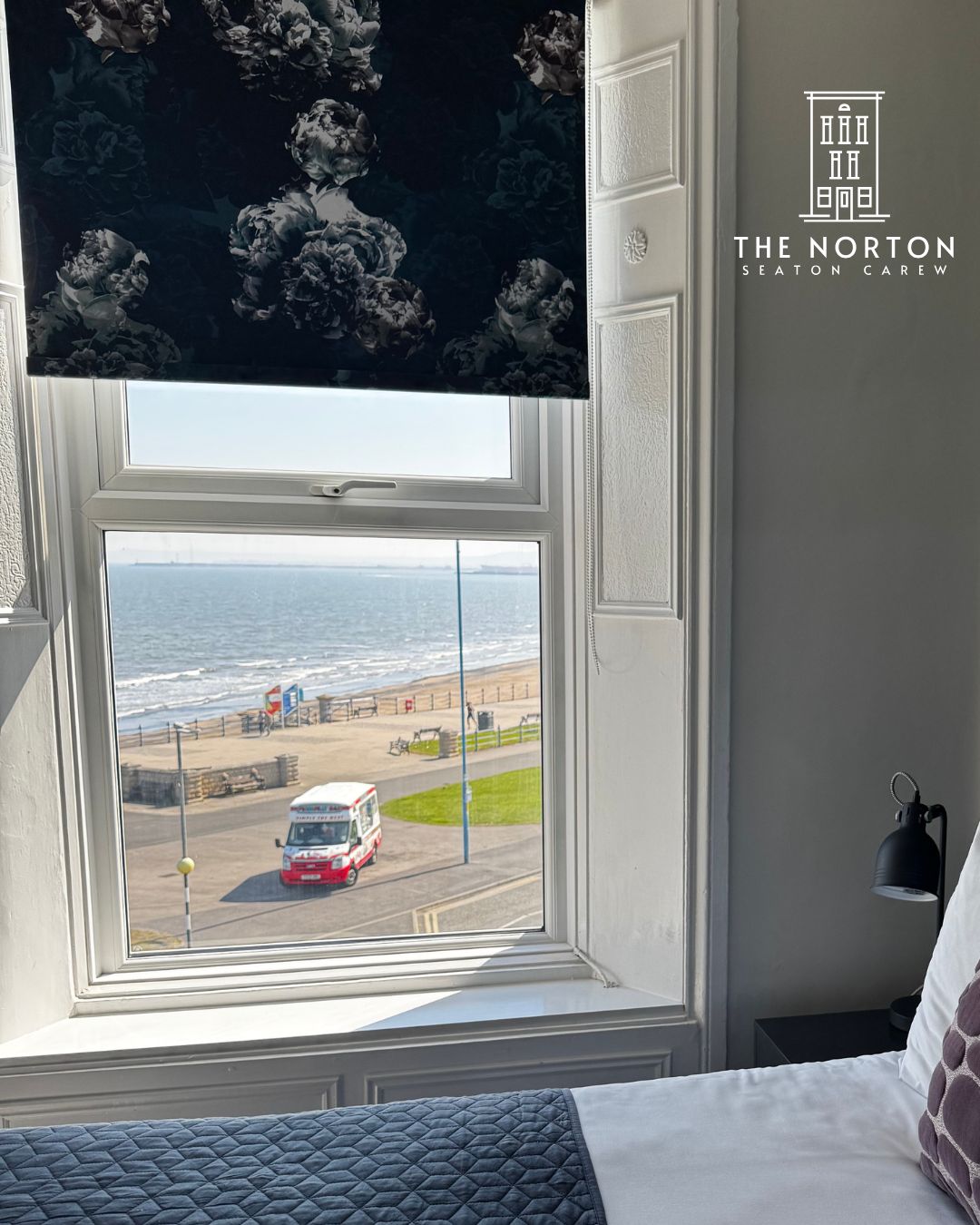 Blackout blind in a Norton guest room, with sea view through the window.